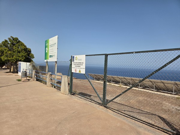 Valla de la estación de bombeo de aguas residuales costanera con el mar al fondo