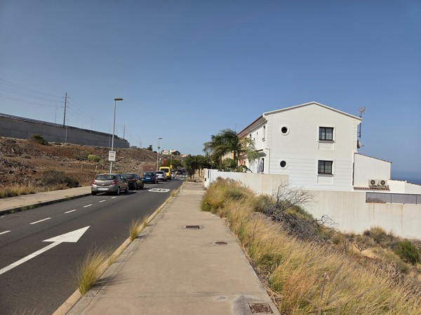 Calle residencial tranquila con acera amplia y viviendas blancas en Costanera