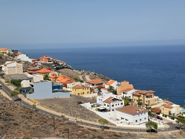 Detalle de las viviendas y la línea de costa con el mar azul profundo en Costanera