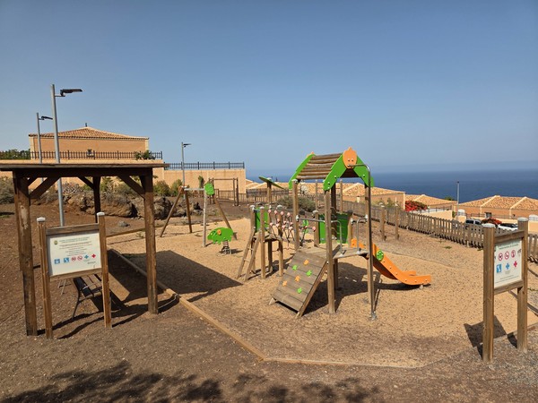 Parque infantil de madera con tobogán y vistas al mar en Costanera