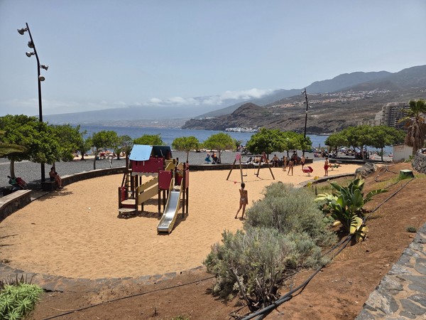 Zona infantil con columpios y toboganes junto al mar en la playa de Radazul, ideal para familias con niños.